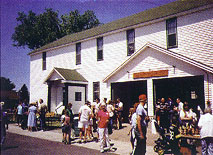 Historic two-story white building with a crowd gathered outside.