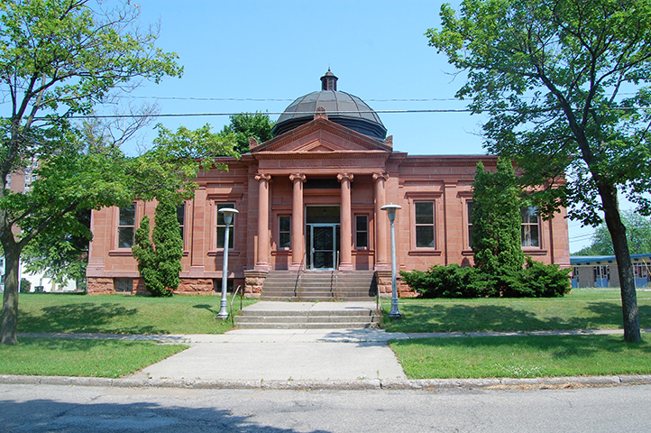 Neo-classical sandstone library with columns and a dome, fronted by steps.
