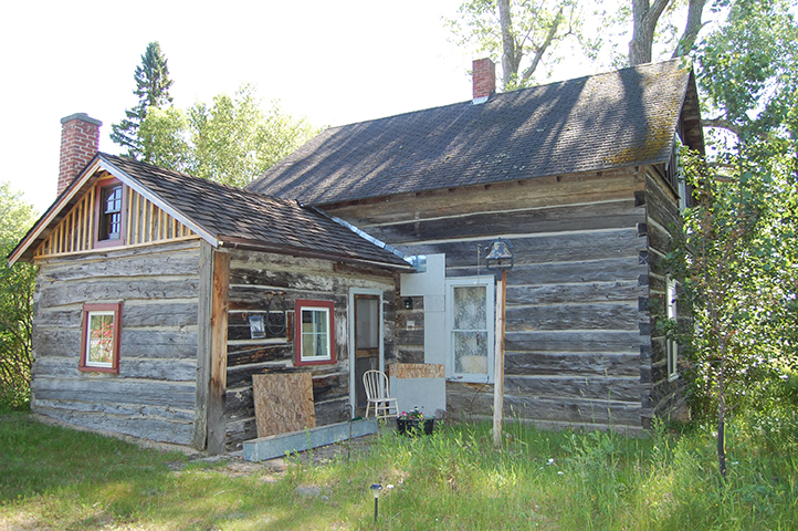 Historic log house with a pitched roof and wooden additions.