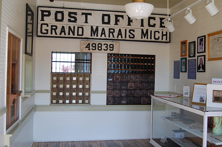Historic Grand Marais Post Office display with mailboxes and signage.