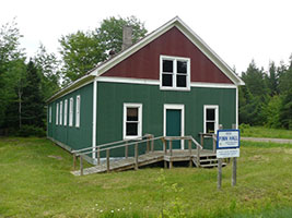 Restored green and red Finnish social hall on Sugar Island, once a hub for immigrant gatherings.