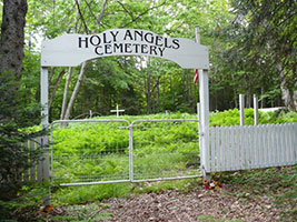 White gate marking entrance to Holy Angels Cemetery, nestled in forest near Payment on Sugar Island.