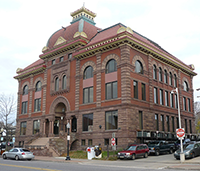 Large historic red brick building with arched windows and a distinctive domed roof.