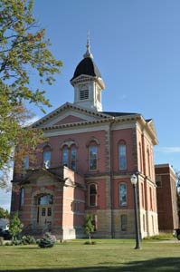 Tall red-brick courthouse with arched windows and a central dome against a clear blue sky.