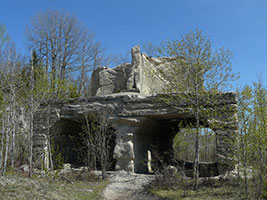 Ruins of a limestone structure at Fiborn Quarry surrounded by sparse spring trees and blue sky.