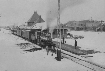  Historic steam train at Ironwood depot, built of red sandstone in 1892, shown during snowy winter.