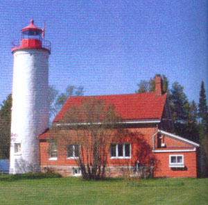  White conical Jacobsville Lighthouse with red-roofed keeper’s house, now a bed and breakfast.