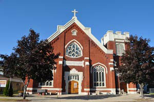 Red-brick church with large stained glass windows, now home to the Menominee Heritage Museum.