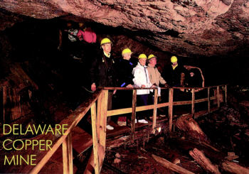 Visitors in hard hats walk through historic underground tunnel at Delaware Copper Mine tour site.