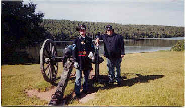 Two men pose by historic cannon at Fort Wilkins State Park, a restored 1844 military outpost.