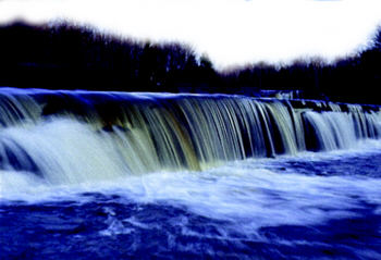 Smooth curtain of water flowing over Silver City Falls with forest in the background.