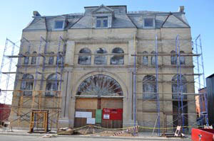 Historic opera house under restoration with scaffolding on its front facade.