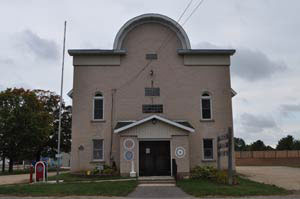 Two-story Pioneer Grange Hall with arched roofline and small front porch.