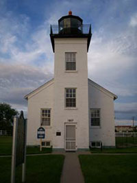  White brick Sand Point Lighthouse with central tower, built in 1867 and now a public museum.