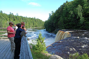 Visitors look out over the Upper Tahquamenon Falls from a wooden observation deck.