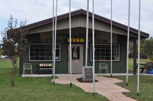 Small Vietnam Veterans Museum building with flagpoles and a memorial plaque out front.